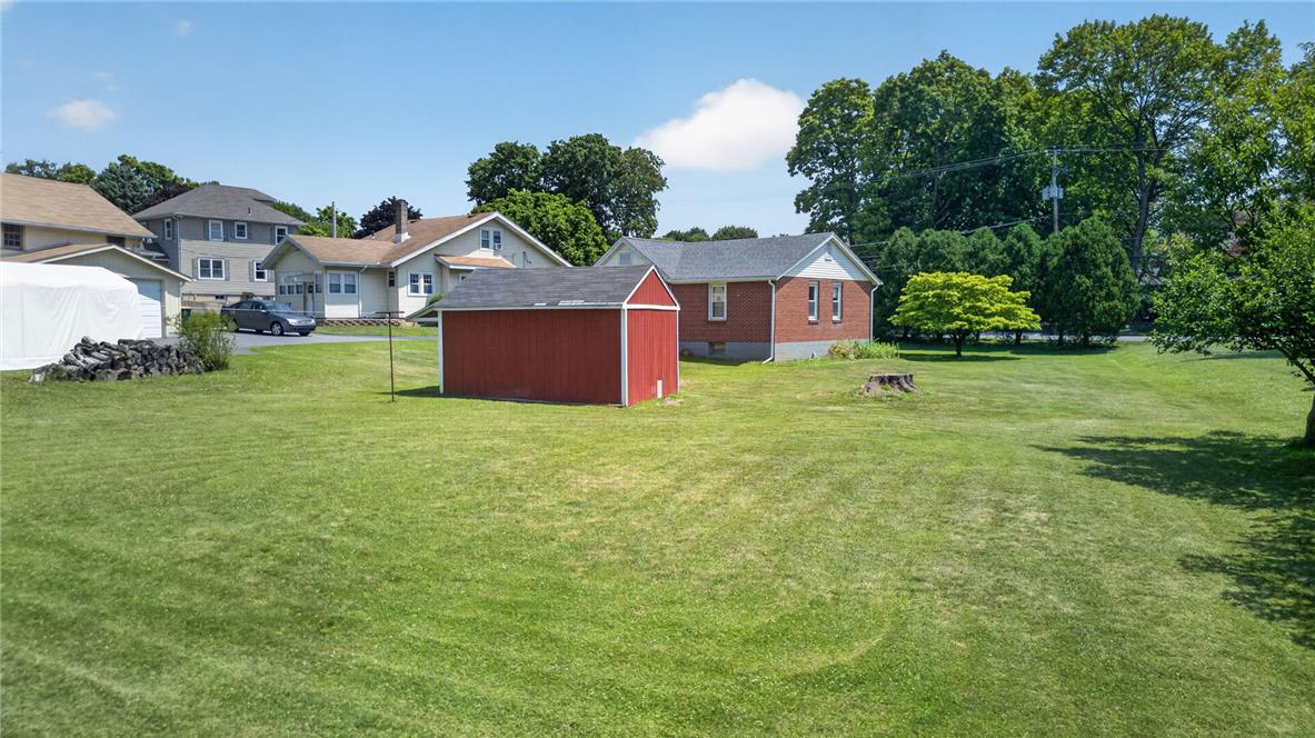 1166 Stones Crossing Road Easton, PA 18045 - Photo 19 of 35 A spacious, verdant yard with an adjacent red storage shed, offering ample outdoor potential.