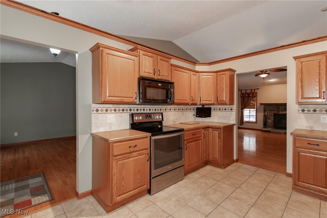 4815 South Ridge Road Perry, OH 44081 - Photo 5 of 48 Kitchen with stainless steel range with electric stovetop, backsplash, lofted ceiling, black microwave, and light tile patterned floors