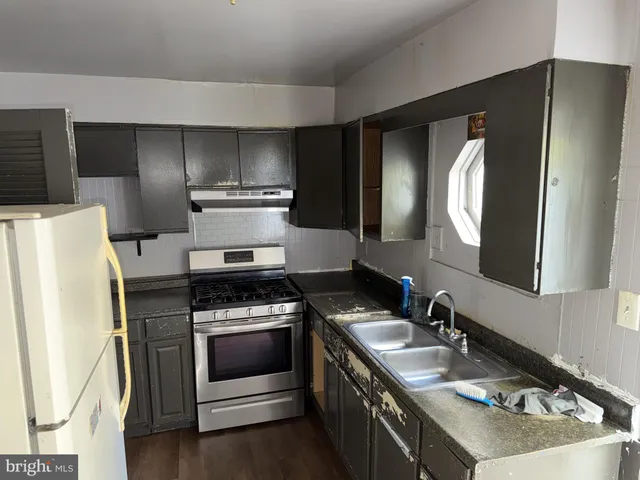a kitchen with granite countertop a refrigerator stove and sink