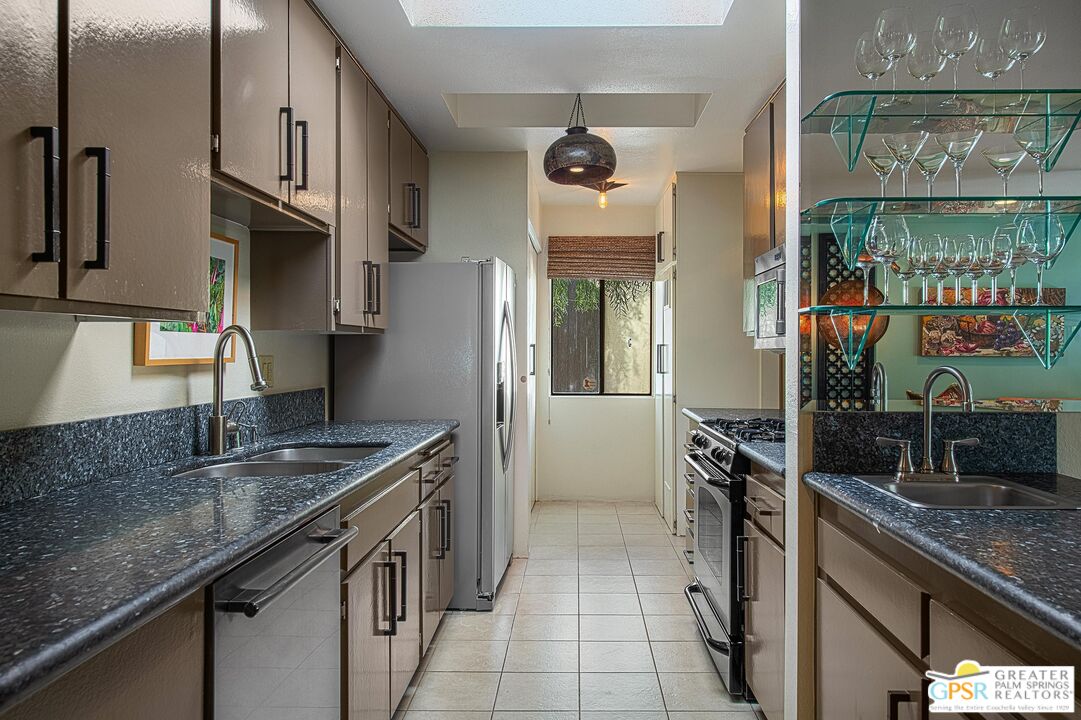 1177 East Alejo Road Palm Springs, CA 92262 - Photo 13 of 33 a kitchen with stainless steel appliances granite countertop a sink stove and refrigerator