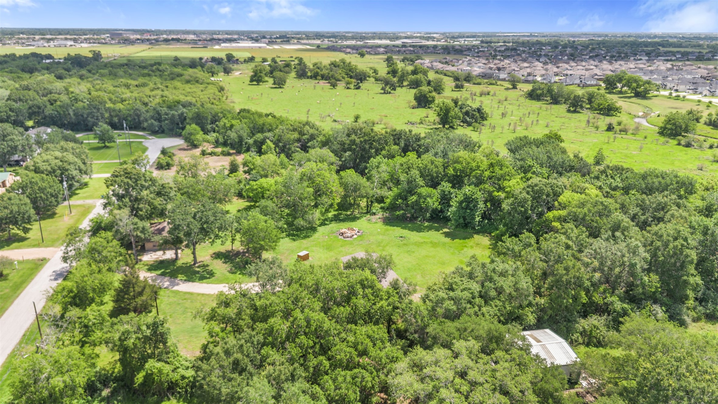 2701 Mazen Road Rosenberg, TX 77471 - Photo 5 of 10 This aerial photo showcases a spacious, lush green property surrounded by mature trees, offering a serene and private setting. Nearby, a residential area and open fields provide a balance of community and nature. Ideal for those seeking tranquility with convenient access to city amenities.