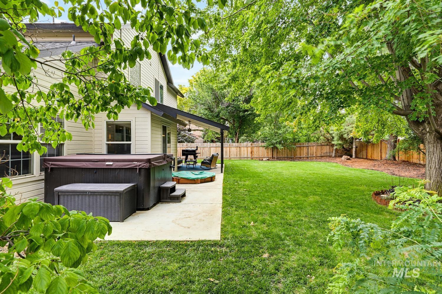 369 South Winthrop Way Boise, ID 83709 - Photo 43 of 50 Spacious backyard featuring a large concrete patio, built-in spa, expansive lawn, mature shade trees, and privacy fencing
