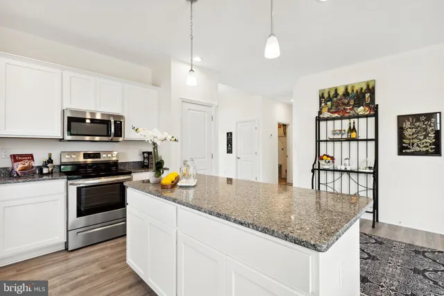 a kitchen with stainless steel appliances granite countertop a stove top oven a sink a counter space and cabinets