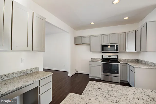 a kitchen with granite countertop a stove a sink and a microwave