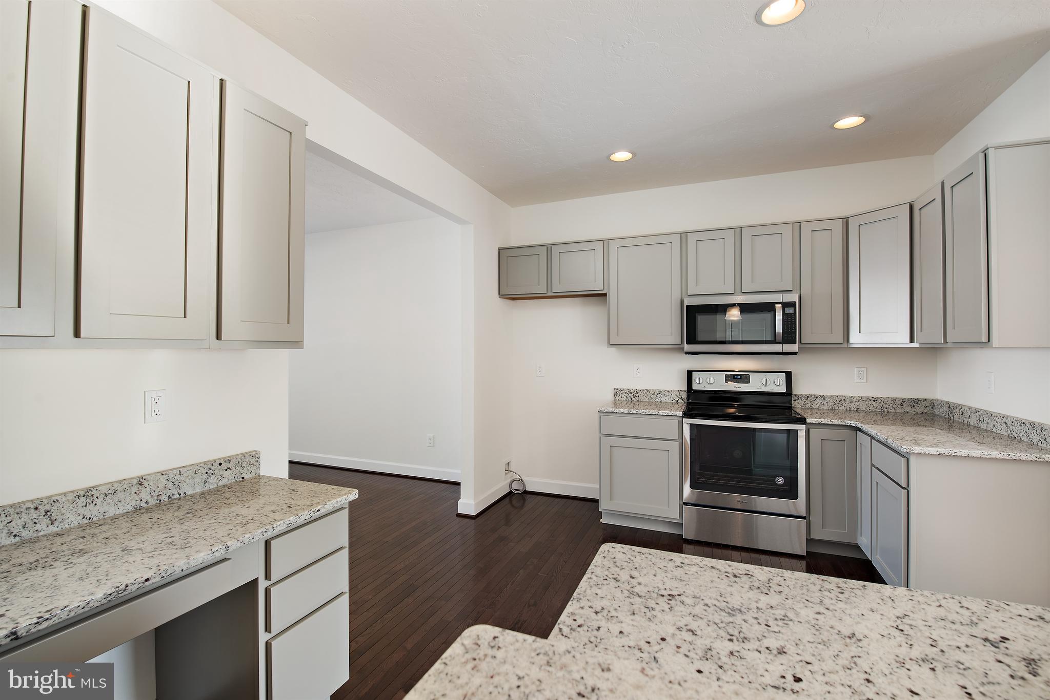 185 East Audubon Drive, Unit 177 Gettysburg, PA 17325 - Photo 8 of 36 a kitchen with granite countertop a stove a sink and a microwave