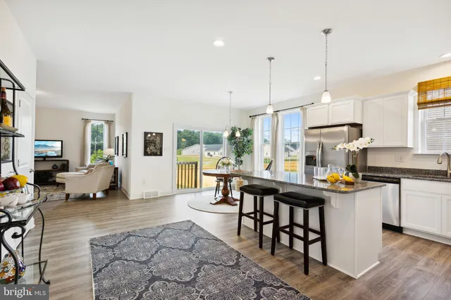 a kitchen with stainless steel appliances granite countertop a stove top oven a sink a dining table and chairs