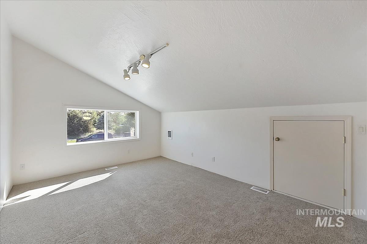 2804 West Sunrise Rim Road Boise, ID 83705 - Photo 29 of 50 Spacious room featuring vaulted ceilings, track lighting, and soft gray carpeting
