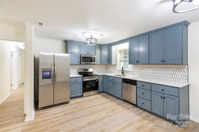 a kitchen with stainless steel appliances granite countertop a refrigerator a sink dishwasher a stove with wooden cabinets and floor