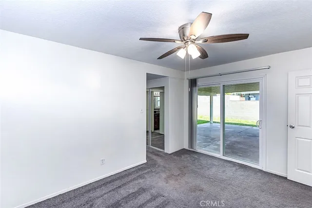 a view of an empty room with window and chandelier fan