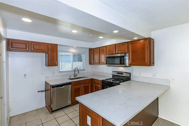 a kitchen with stainless steel appliances a sink a stove a microwave a refrigerator a sink and cabinets