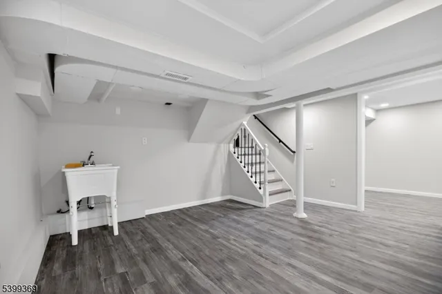 a view of an empty room with wooden floor stairs and a way to ceiling window