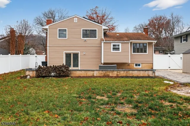a view of a yard in front of a house with plants and large tree