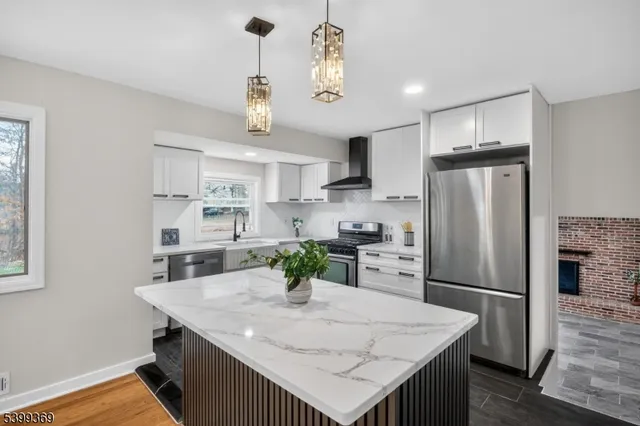 a kitchen with granite countertop a refrigerator a stove a sink dishwasher and white cabinets with wooden floor