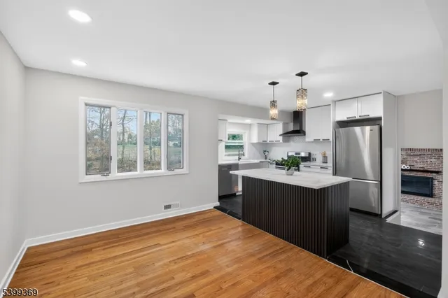 a kitchen with stainless steel appliances granite countertop a refrigerator a sink dishwasher a stove and white countertops with wooden floor