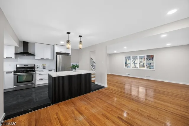 a large kitchen with kitchen island a sink dishwasher stove and oven with wooden floor