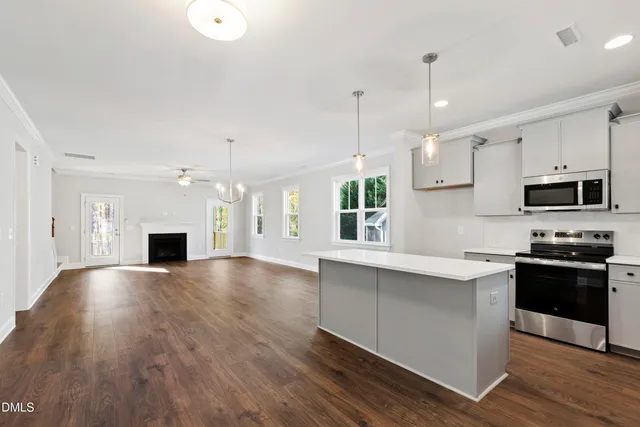 a view of an empty room with wooden floor and a fireplace