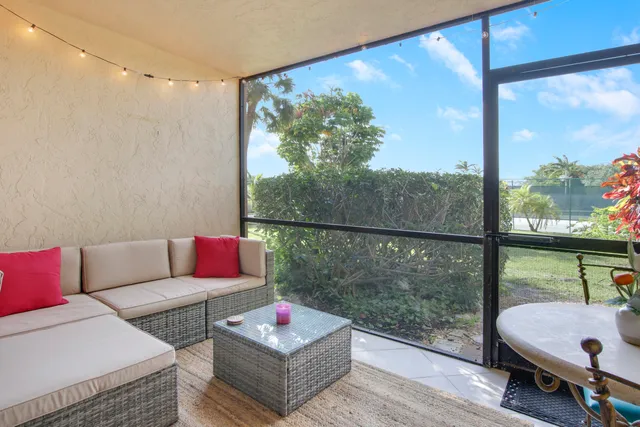 a living room with patio furniture and a floor to ceiling window