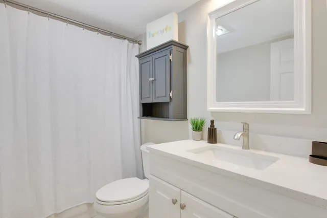 a bathroom with a granite countertop sink mirror vanity and toilet