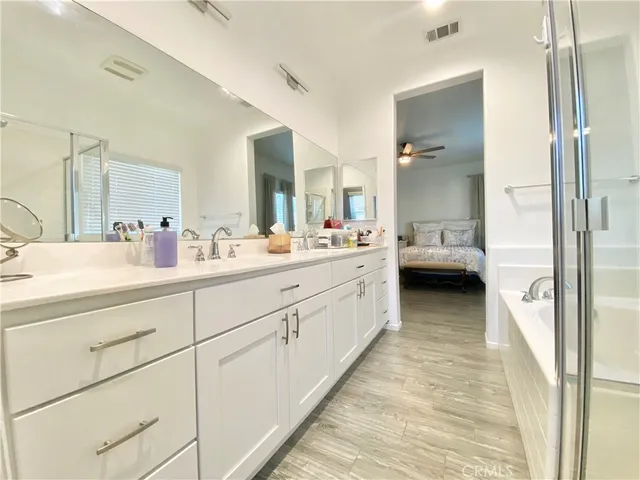a spacious bedroom with a bed a couch and a chandelier fan