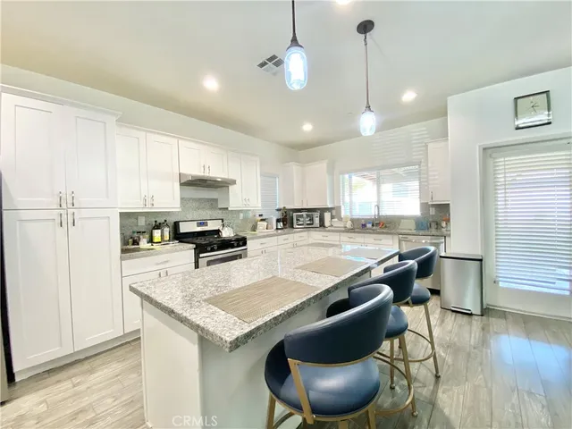 a kitchen with granite countertop wooden floors and white cabinets