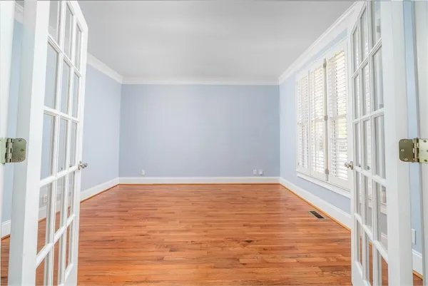 a view of an empty room with wooden floor and a window