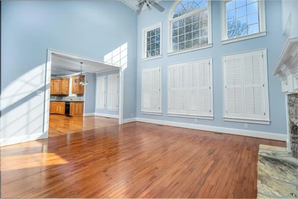 a view of an empty room with wooden floor and a window