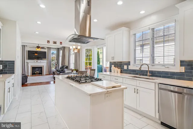 a kitchen with stainless steel appliances kitchen island granite countertop a dining table chairs and white cabinets