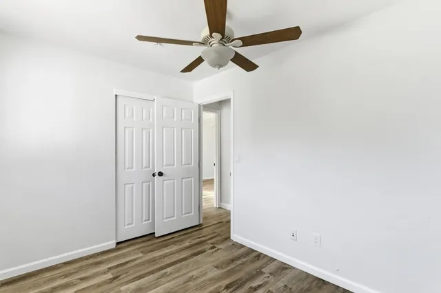 an empty room with wooden floor ceiling fan and window