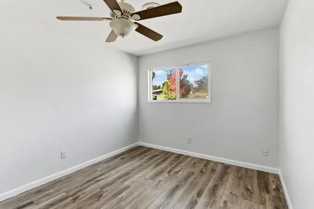 an empty room with wooden floor and ceiling fan