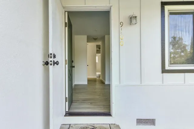 a view of a hallway with wooden floor and a bathroom