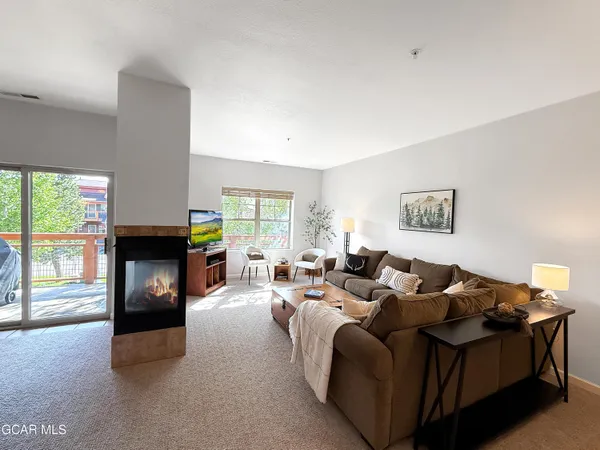 a living room with furniture a fireplace and a floor to ceiling window