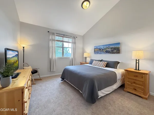 a bedroom with a bed and a flat tv screen on dresser