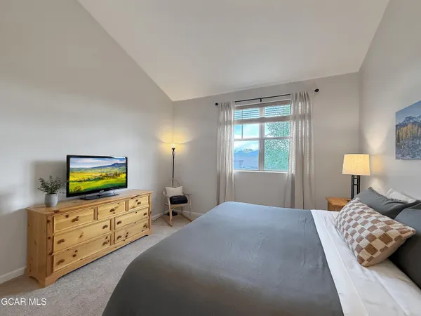 a bedroom with a bed and flat tv screen on dresser