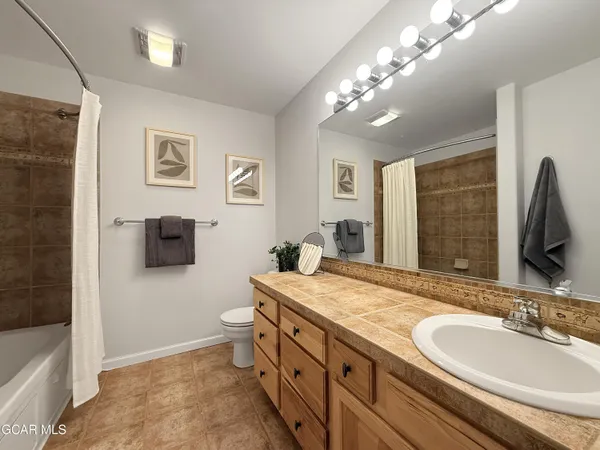 a bathroom with a granite countertop double vanity sink a mirror and a bathtub