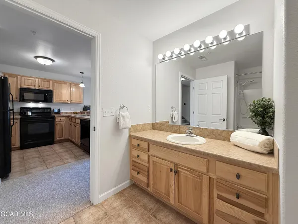 a spacious bathroom with a granite countertop sink a large mirror and a refrigerator