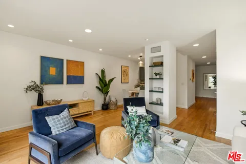 a living room with furniture kitchen view and a potted plant