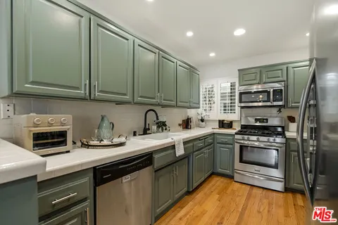 a kitchen with stainless steel appliances granite countertop a sink a stove and a refrigerator