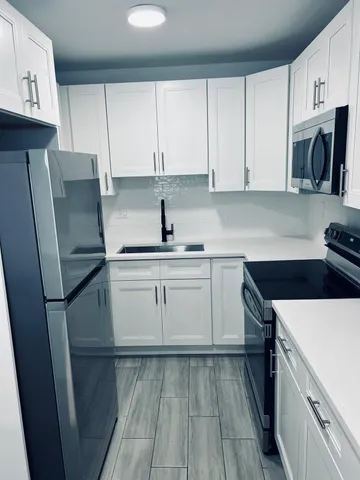 a kitchen with a refrigerator sink and cabinets