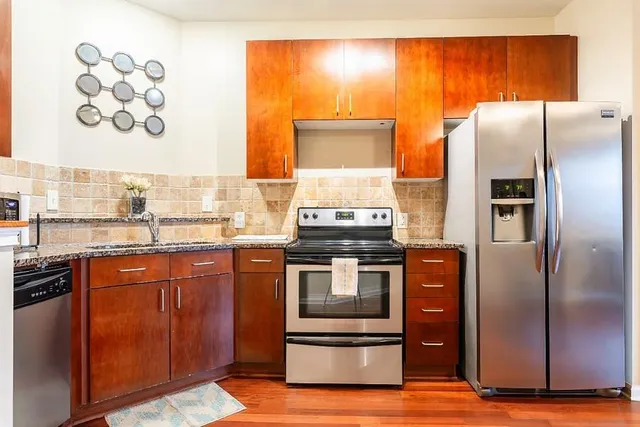 a kitchen with stainless steel appliances granite countertop a refrigerator and a stove