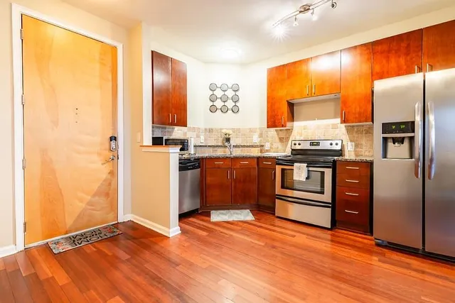 a kitchen with stainless steel appliances granite countertop a refrigerator a sink and a stove