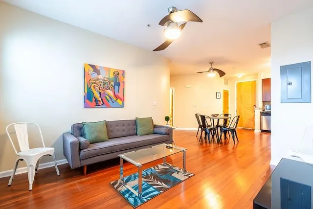 a living room with furniture and a dining table with wooden floor