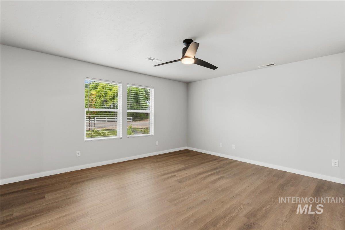 12475 West Victory Road Boise, ID 83709 - Photo 8 of 26 Spacious room featuring wood-finish flooring, light gray walls, and a contemporary ceiling fan with integrated lighting