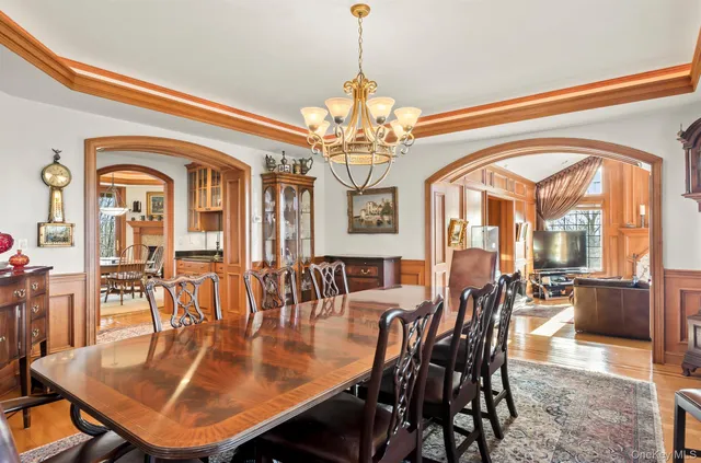 a dining room with wooden floor a chandelier a wooden table and chairs