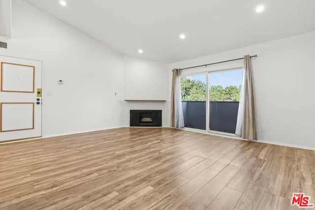 a view of empty room with wooden floor and fireplace
