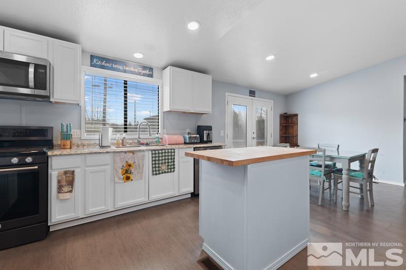 3885 Puffin Street Reno, NV 89508 - Photo 8 of 18 a kitchen with stainless steel appliances kitchen island granite countertop a stove a sink a microwave a dining table and chairs