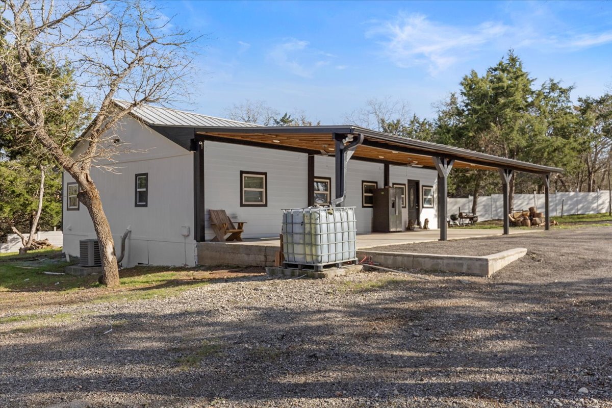 240 Riddle Road Cedar Creek, TX 78612 - Photo 5 of 31 a view of a white house with large windows and a small yard