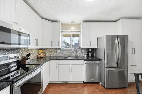 a kitchen with a sink a refrigerator and white cabinets