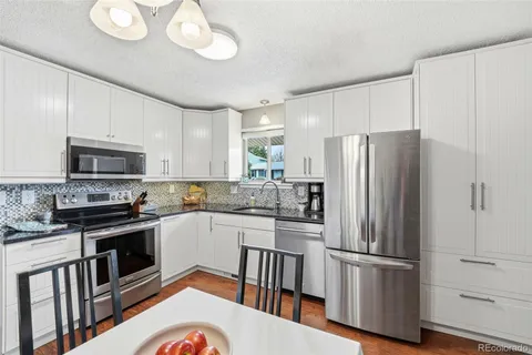 a kitchen with stainless steel appliances a refrigerator a stove a sink cabinets and a dining table