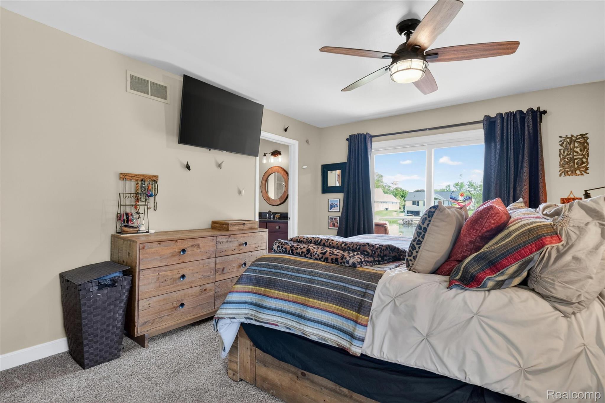 3860 East Commerce Road Commerce Township, MI 48382 - Photo 29 of 72 Carpeted bedroom featuring a ceiling fan with integrated lighting, a broad window overlooking a body of water, and a wooden dresser