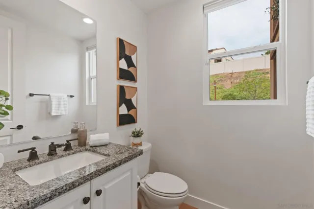 a bathroom with a granite countertop sink mirror vanity and toilet
